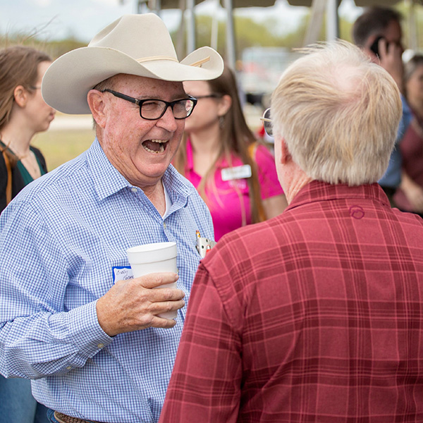 Group of people at a community event, two men talking and laughing