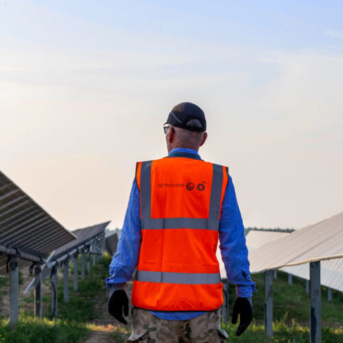 Man wearing a bright orange high-visibility PPE vest with 